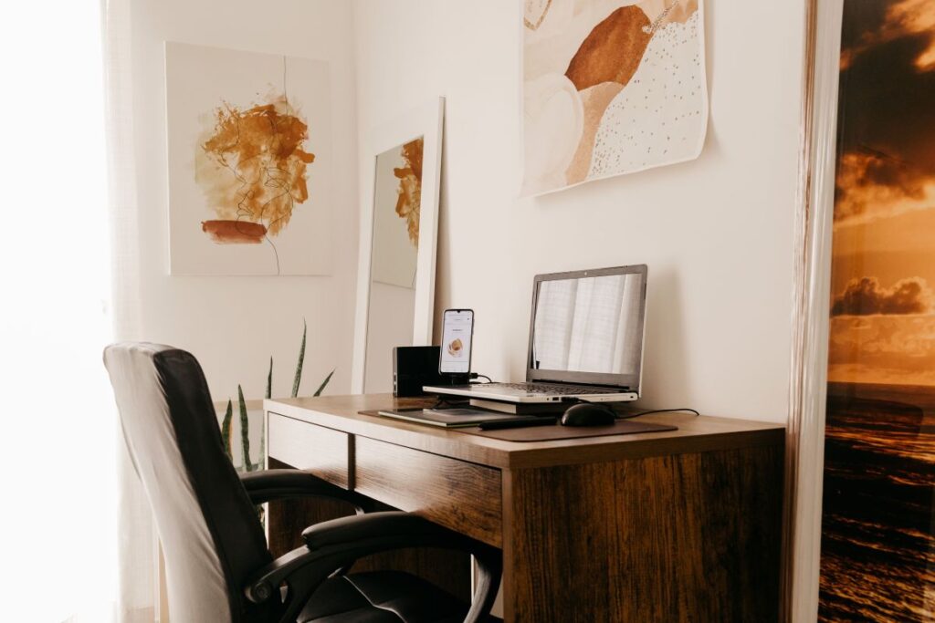 wooden narrow desk setup with laptop and office chair in small bedroom corner
